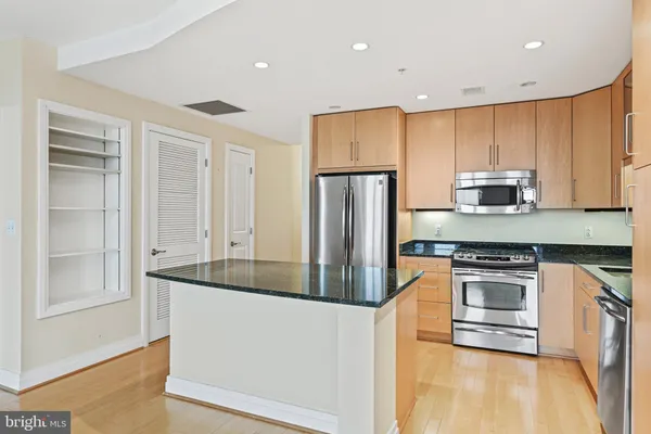 a kitchen with stainless steel appliances granite countertop a refrigerator a stove and a sink with wooden floor