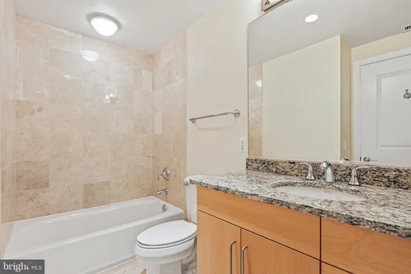 a bathroom with a granite countertop toilet a sink and a bathtub