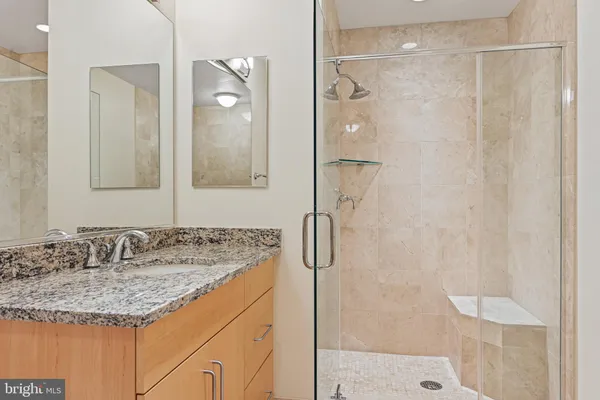 a bathroom with a granite countertop sink mirror and shower