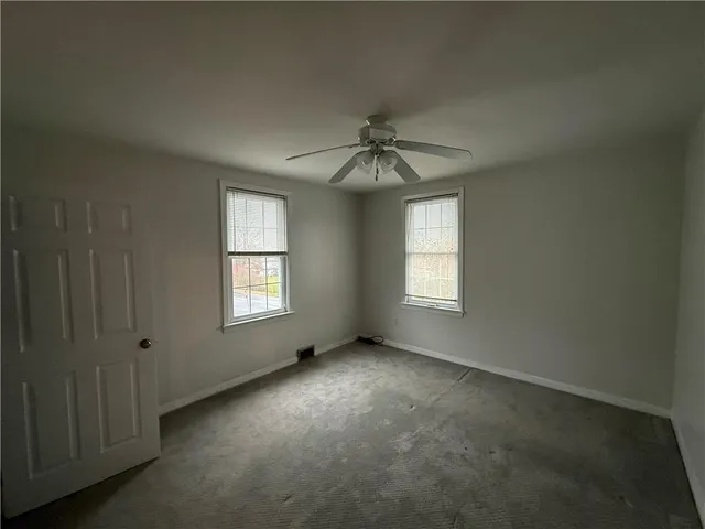 an empty room with windows and chandelier fan