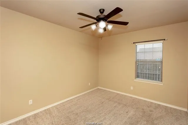 an empty room with a ceiling fan and a window