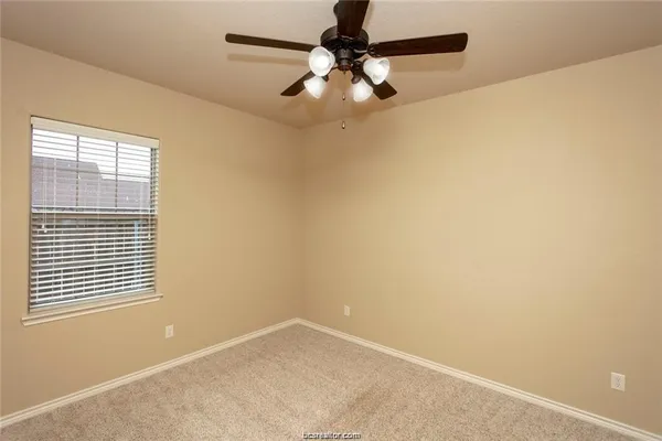 an empty room with a window and a fan