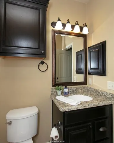 a bathroom with a granite countertop toilet sink and mirror
