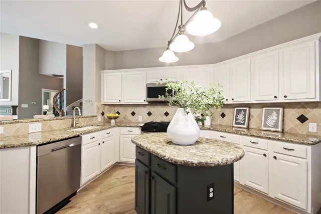 a kitchen with stainless steel appliances granite countertop a sink a stove and cabinets