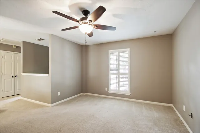 an empty room with windows and fan