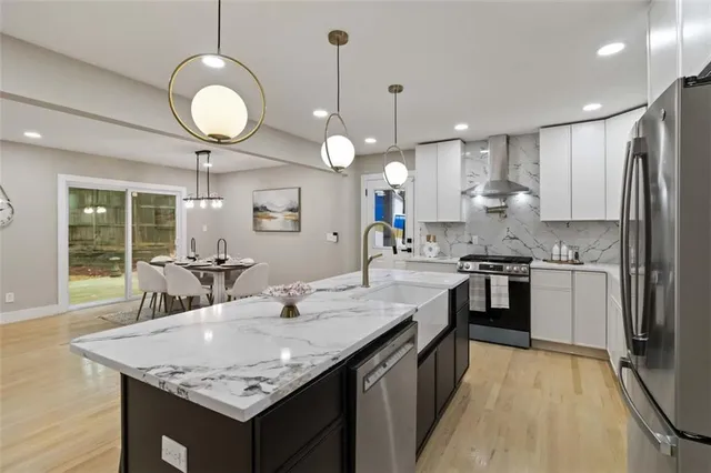 a kitchen with stainless steel appliances granite countertop a sink a stove and refrigerator
