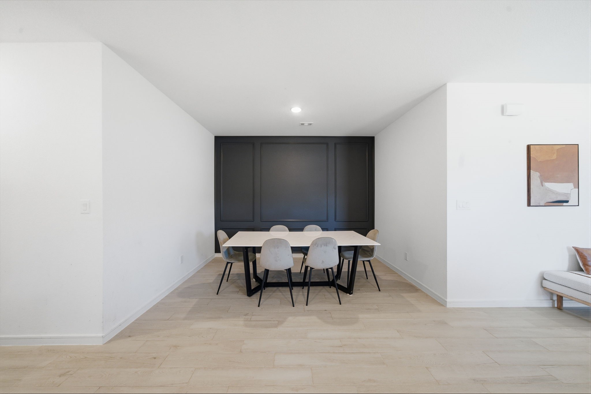 302 Alder Loop Anahuac, TX 77514 - Photo 12 of 34 This dining area features a modern, minimalist design with a sleek black accent wall. The space is bright and open, with light wood look tile flooring and neutral walls.