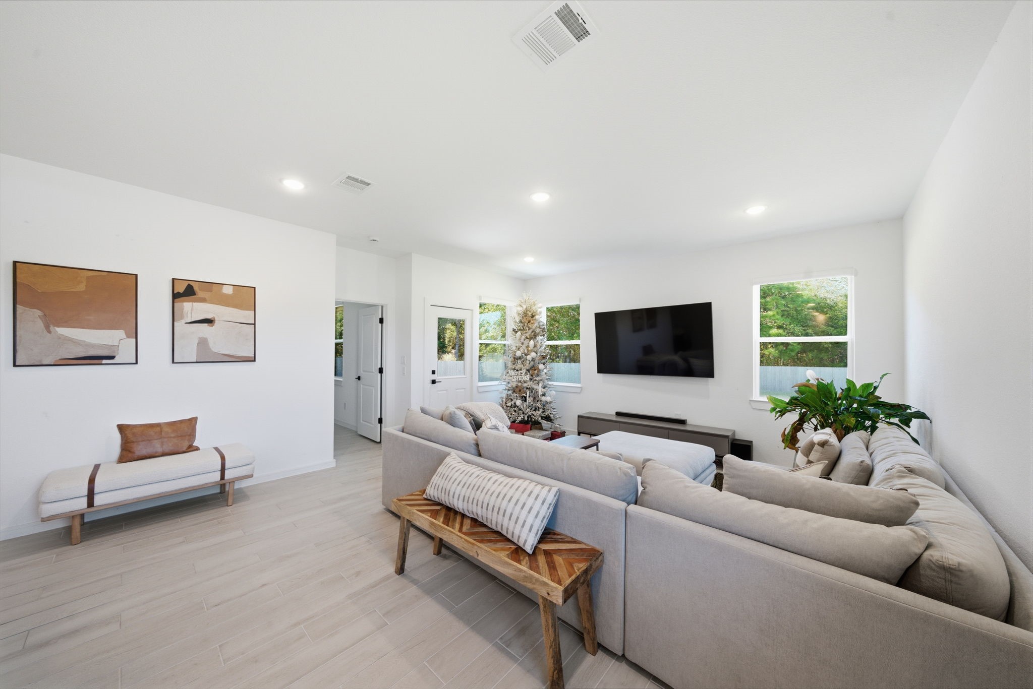 302 Alder Loop Anahuac, TX 77514 - Photo 6 of 34 This spacious living room features a large sectional sofa, a mounted TV, and abundant natural light from multiple windows. The neutral tones and minimalist decor create a welcoming and modern atmosphere.