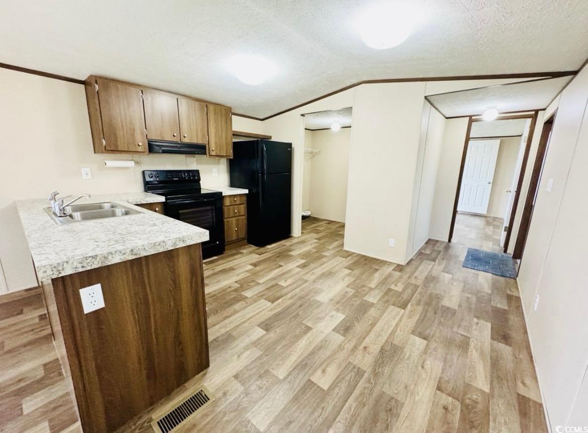 2433 Old Corner Court Marion, SC 29571 - Photo 11 of 18 Kitchen with light countertops, crown molding, black appliances, light wood-type flooring, and vaulted ceiling
