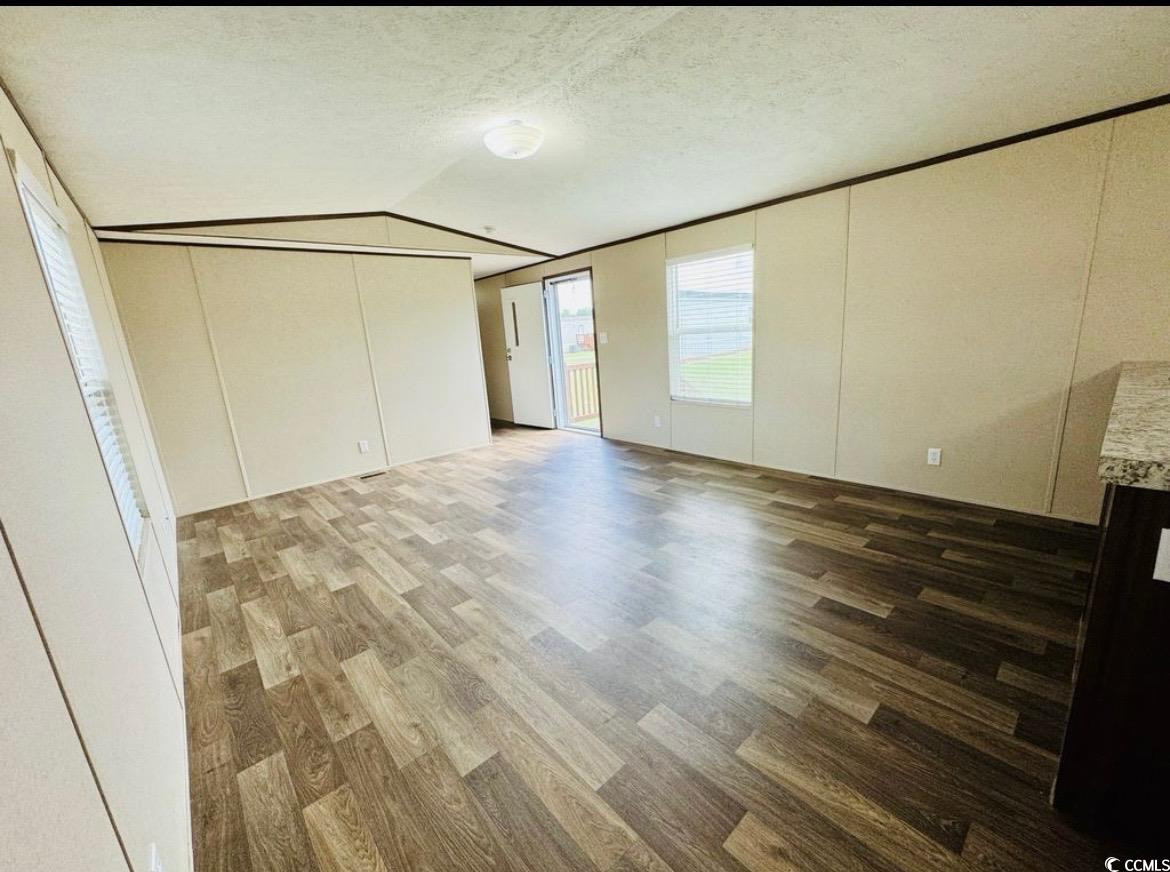 2433 Old Corner Court Marion, SC 29571 - Photo 10 of 18 Unfurnished living room with lofted ceiling, wood finished floors, a textured ceiling, and a decorative wall