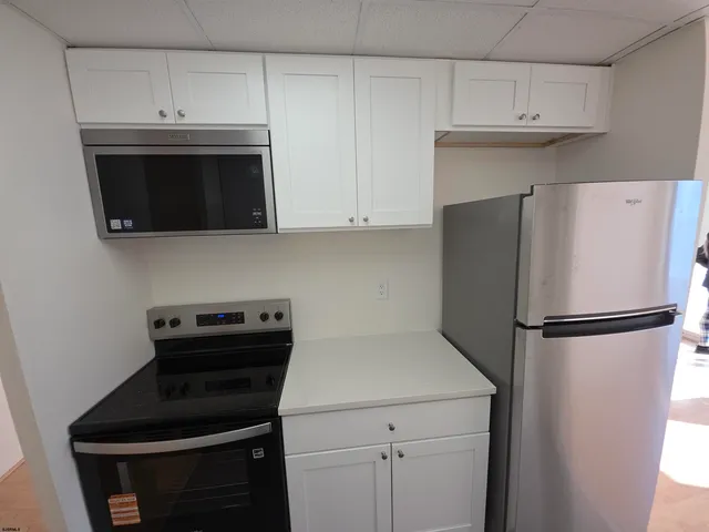 a white kitchen with a refrigerator stove and cabinets