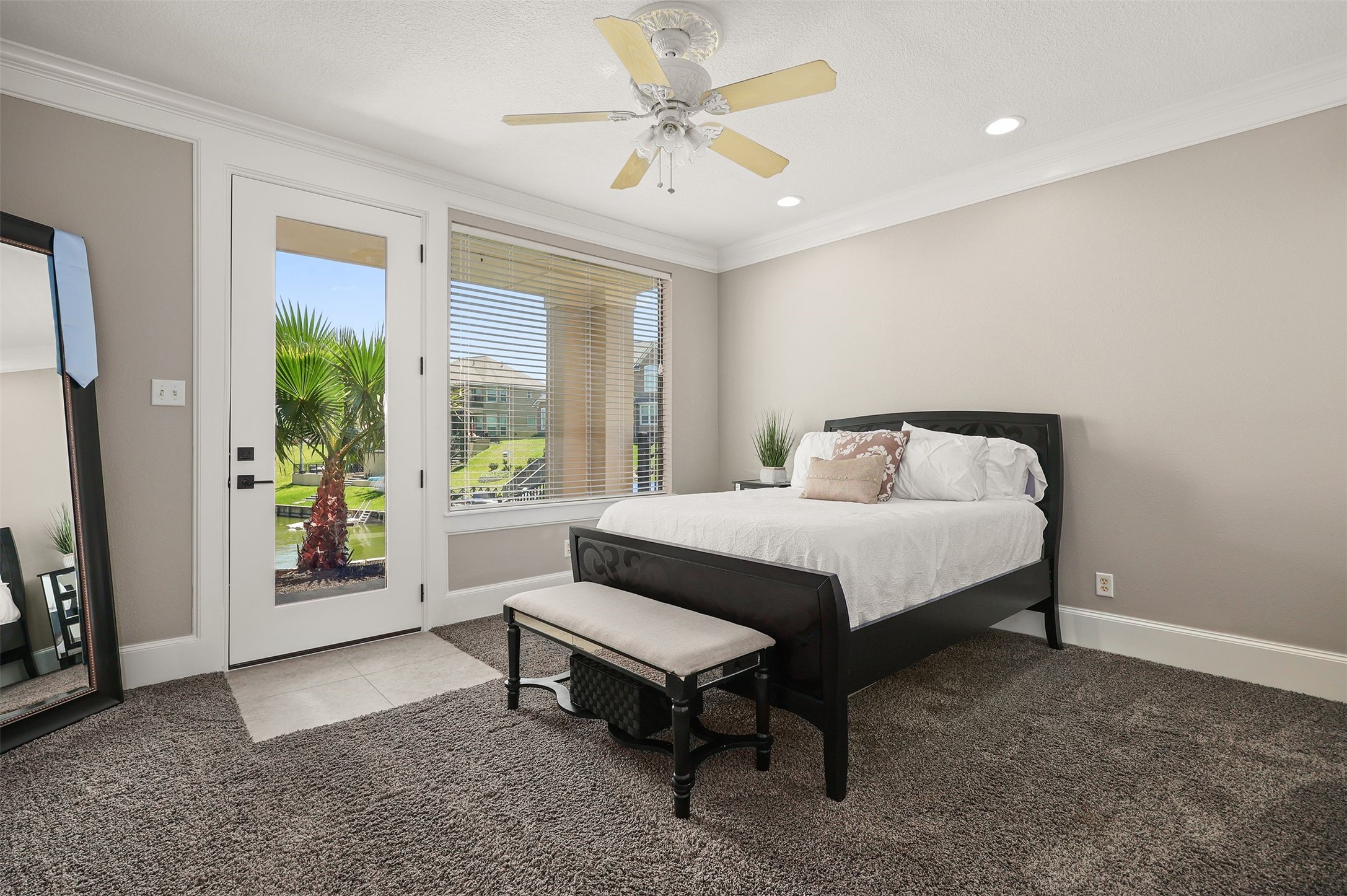 10896 Decatur Street Willis, TX 77318 - Photo 40 of 50 This bright bedroom offers ample natural light and scenic views through a large window and glass door, featuring a cozy bed with a bench, plush carpeting, and a ceiling fan, all set against neutral walls and modern decor for a welcoming atmosphere.