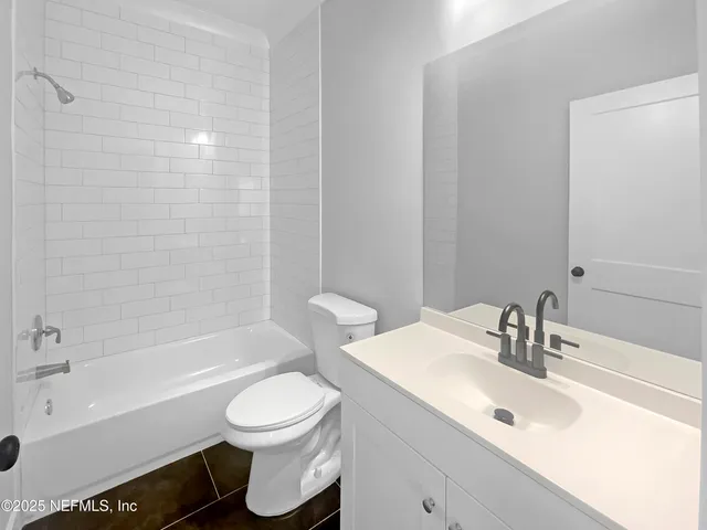 a bathroom with a bathtub shower sink vanity mirror and toilet