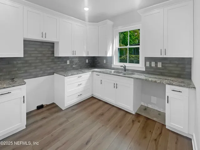 a kitchen with granite countertop white cabinets white appliances a sink and a window