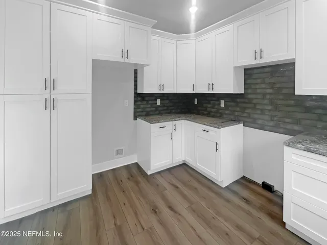 a kitchen with granite countertop white cabinets and wooden floor