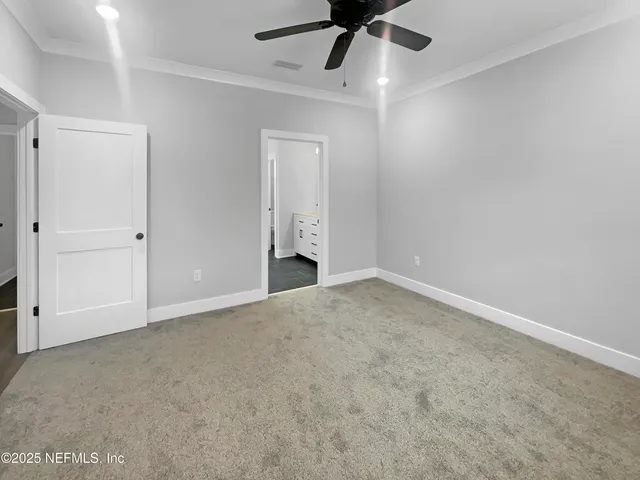 an empty room with a ceiling fan and carpet