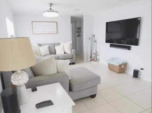 a living room with couches a flat screen tv and kitchen view