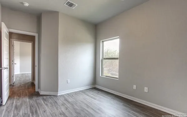 a view of an empty room with wooden floor and closet
