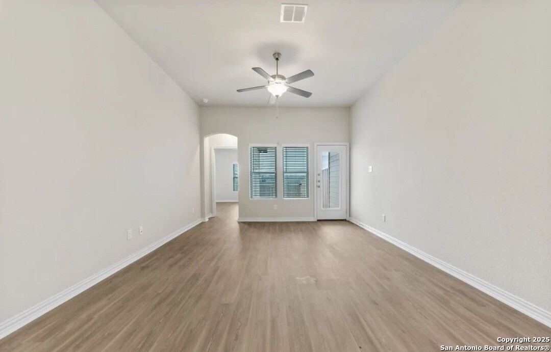 5423 Devils Gate Converse, TX 78109 - Photo 8 of 17 an empty room with wooden floor chandelier fan and windows