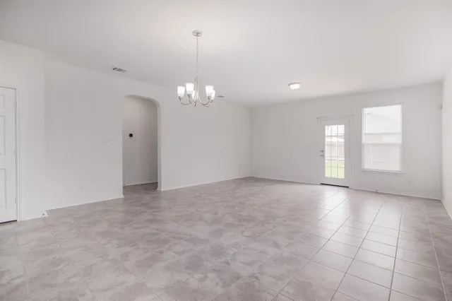 a view of an empty room with a chandelier fan