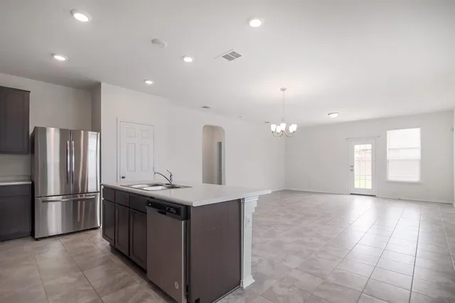 a kitchen with kitchen island granite countertop a sink and refrigerator