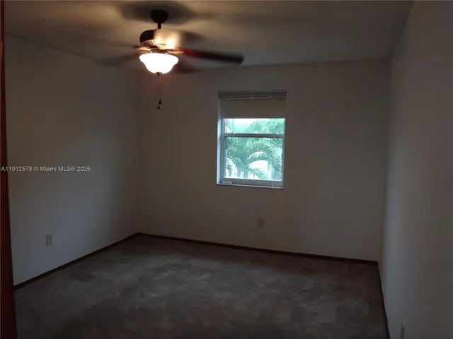 an empty room with a fan & a window