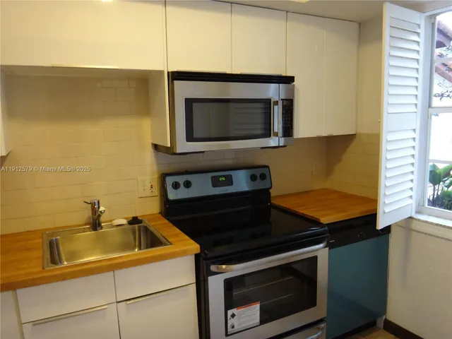 a kitchen with granite countertop cabinets stainless steel appliances and wooden floor