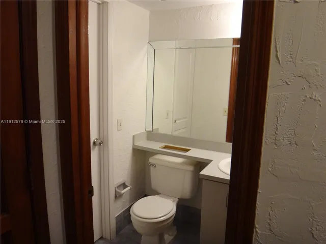 a bathroom with a granite countertop toilet and a sink