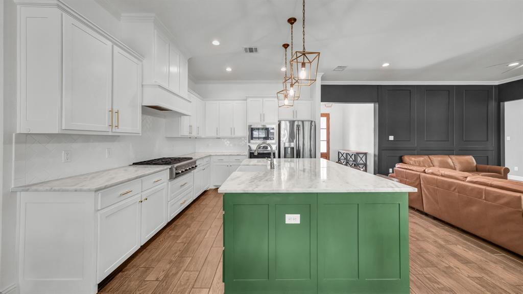 115 Post Oak Way Weatherford, TX 76087 - Photo 37 of 39 Dual tone kitchen with ornamental molding, light stone countertops, an island with sink, open floor plan, and stainless steel appliances