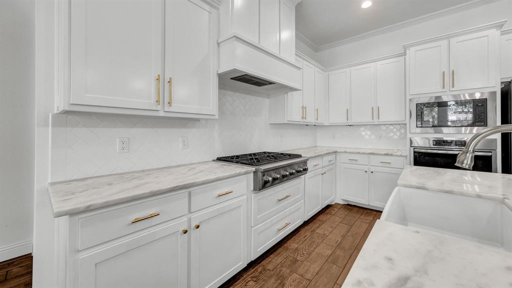 115 Post Oak Way Weatherford, TX 76087 - Photo 11 of 39 Kitchen with white cabinetry, dark wood-style floors, stainless steel appliances, light stone countertops, and ornamental molding