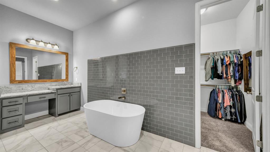 115 Post Oak Way Weatherford, TX 76087 - Photo 18 of 39 Bathroom featuring vanity, a soaking tub, a walk in closet, tile walls, and light marble finish floors