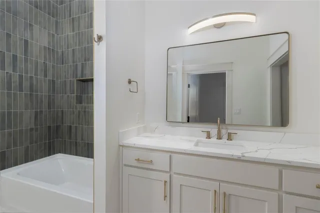 a bathroom with a granite countertop sink mirror and a bathtub