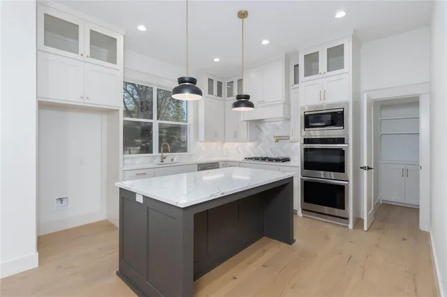 a kitchen with kitchen island a sink stainless steel appliances and cabinets