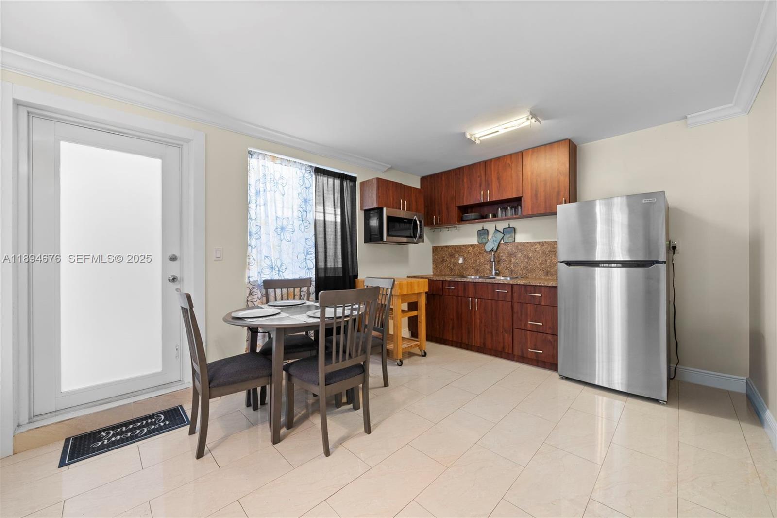 1271 Northwest 87th Street Miami, FL 33147 - Photo 20 of 29 a kitchen with a refrigerator a table and chairs