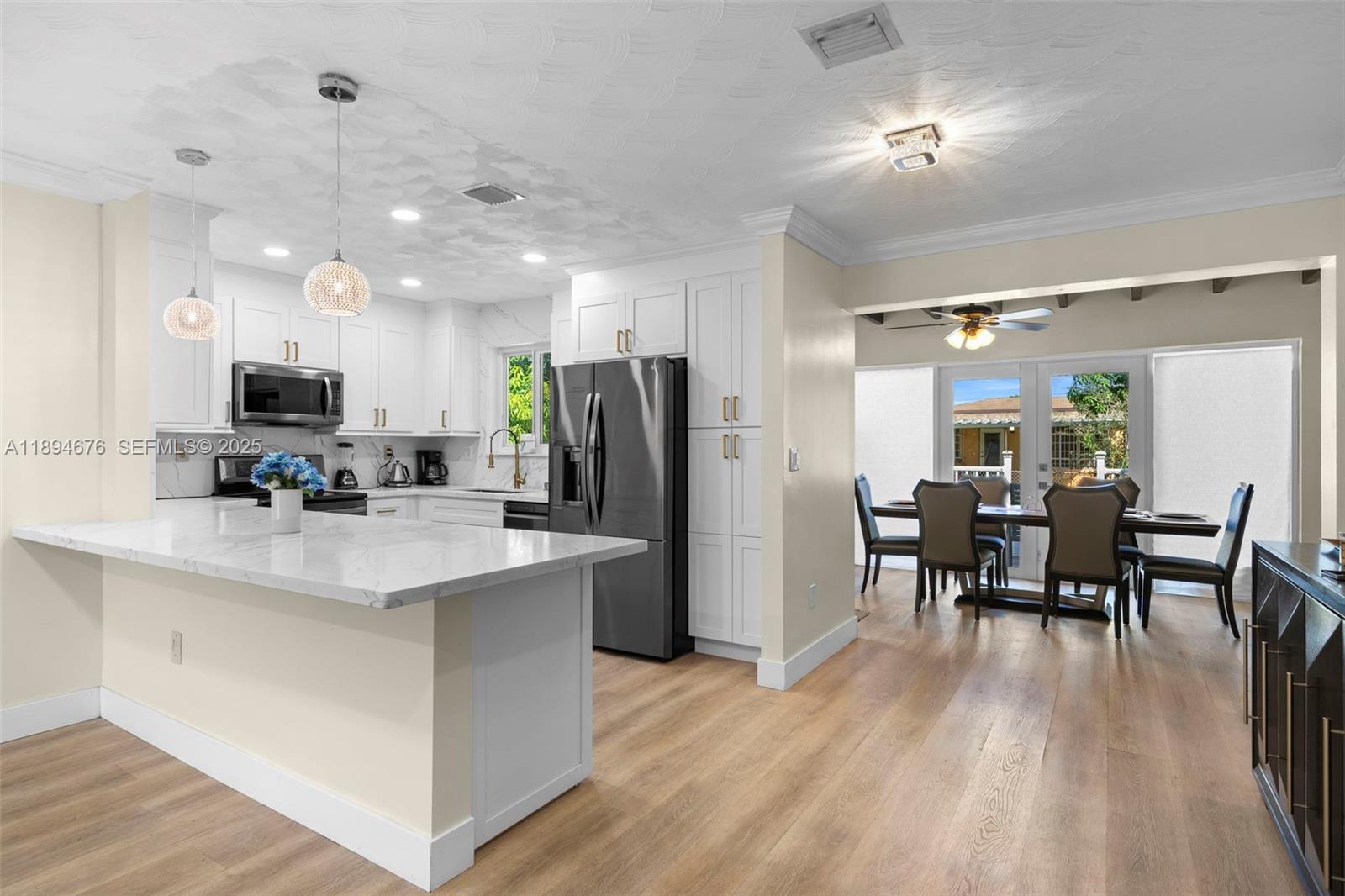 1271 Northwest 87th Street Miami, FL 33147 - Photo 7 of 29 a kitchen with stainless steel appliances a dining table chairs microwave and refrigerator