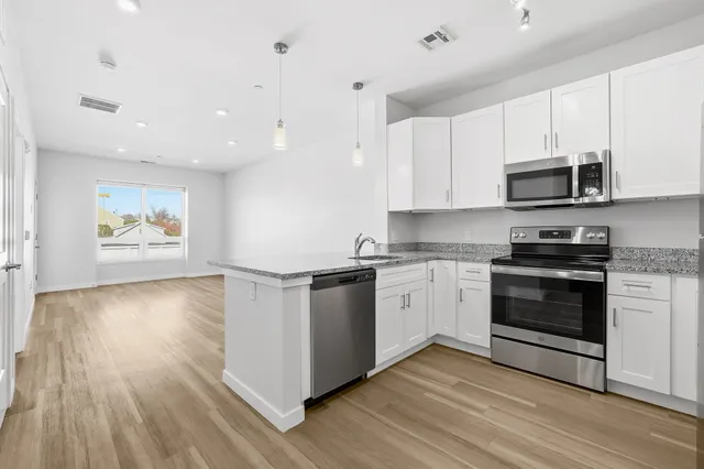 a kitchen with stainless steel appliances granite countertop a stove top oven a sink and white cabinets