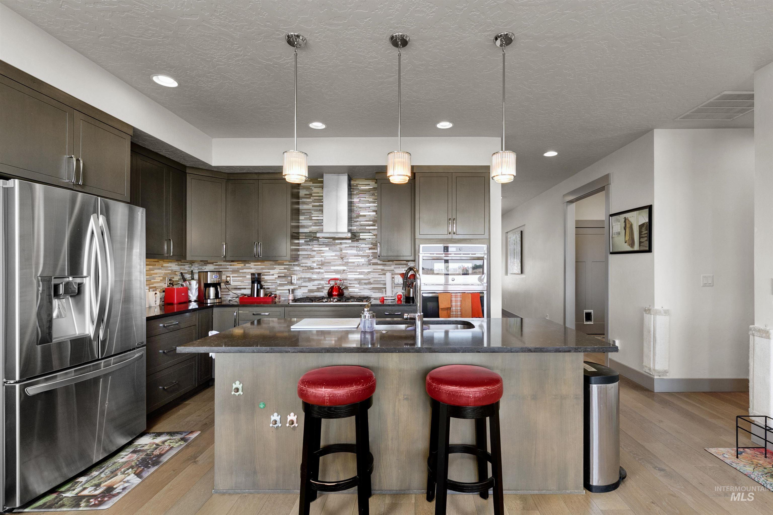 24398 Tombstone Ridge Court Middleton, ID 83644 - Photo 21 of 47 Kitchen featuring stainless steel appliances, dark cabinetry, and a mosaic tile backsplash