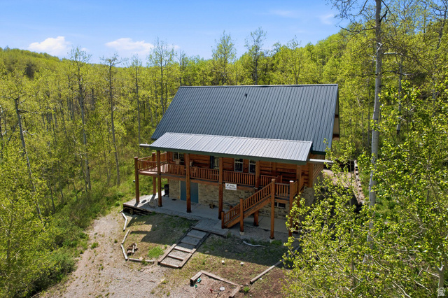 2096 South Aspen Ridge Coalville, UT 84017 - Photo 6 of 44 Log cabin exterior featuring a metal roof, an upper-level balcony, a ground-level patio, and natural wood stairs