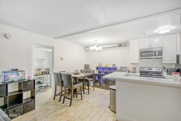 a room with stainless steel appliances kitchen island granite countertop a dining table chairs and a refrigerator