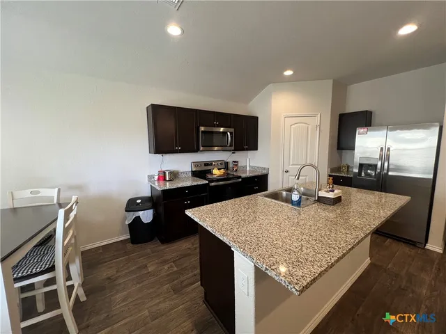 a kitchen with kitchen island granite countertop a stove top oven a sink with granite countertops and chairs