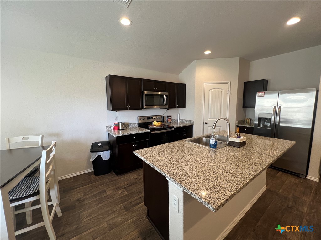 809 Margay Loop Seguin, TX 78155 - Photo 13 of 20 a kitchen with kitchen island granite countertop a stove top oven a sink with granite countertops and chairs
