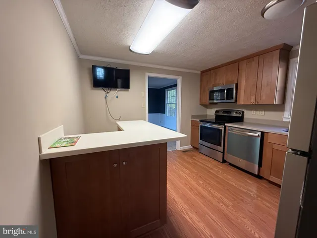 a kitchen with stainless steel appliances a sink a stove top oven a counter space and cabinets