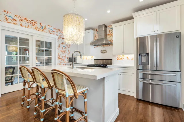 a kitchen with stainless steel appliances a refrigerator a stove a sink dishwasher and white cabinets with wooden floor