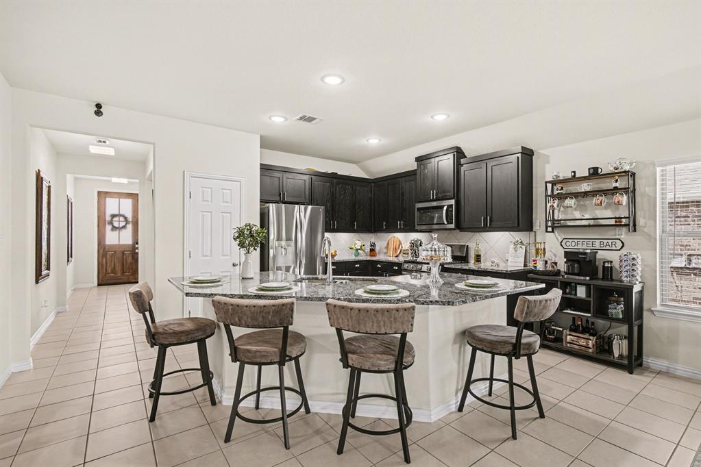 1237 Rushmore Drive Burleson, TX 76028 - Photo 6 of 28 a kitchen with stainless steel appliances kitchen island granite countertop a stove a table and chairs in it