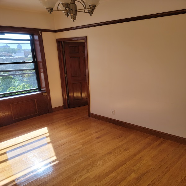 a view of an empty room with a window and wooden floor