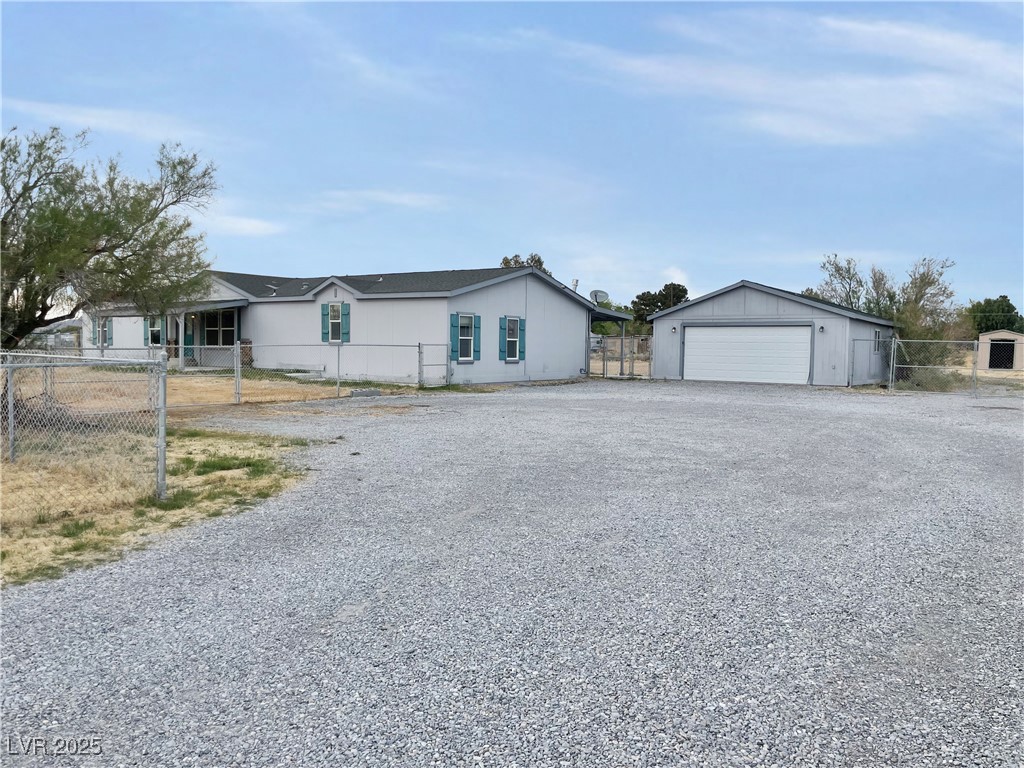 1740 West Wilson Road Pahrump, NV 89048 - Photo 1 of 13 View of front of property featuring a detached garage, fence, and an outdoor structure