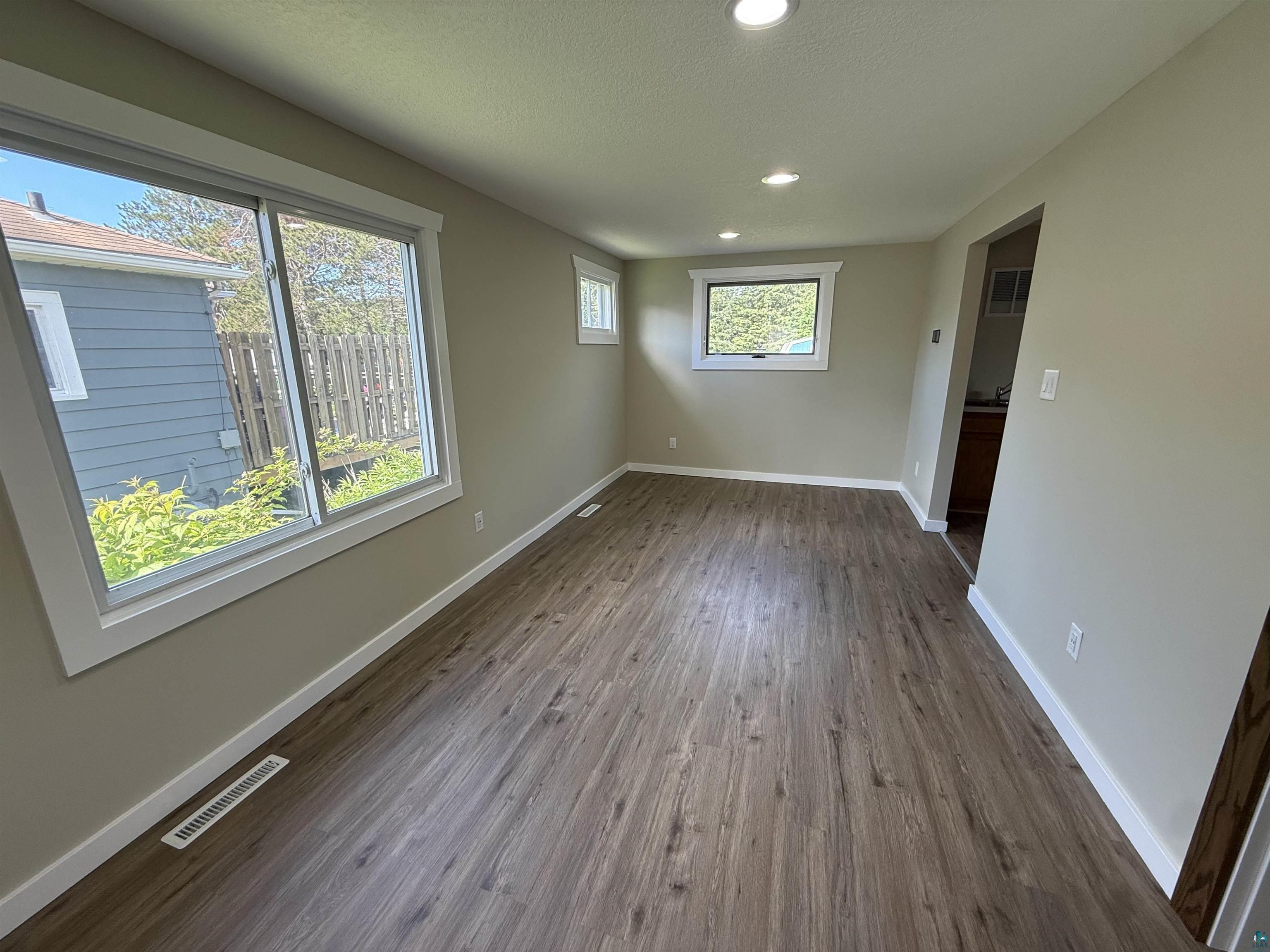 3841 Haines Road Hermantown, MN 55811 - Photo 4 of 11 Spacious room featuring wood-finish flooring, recessed lighting, and multiple windows with white trim