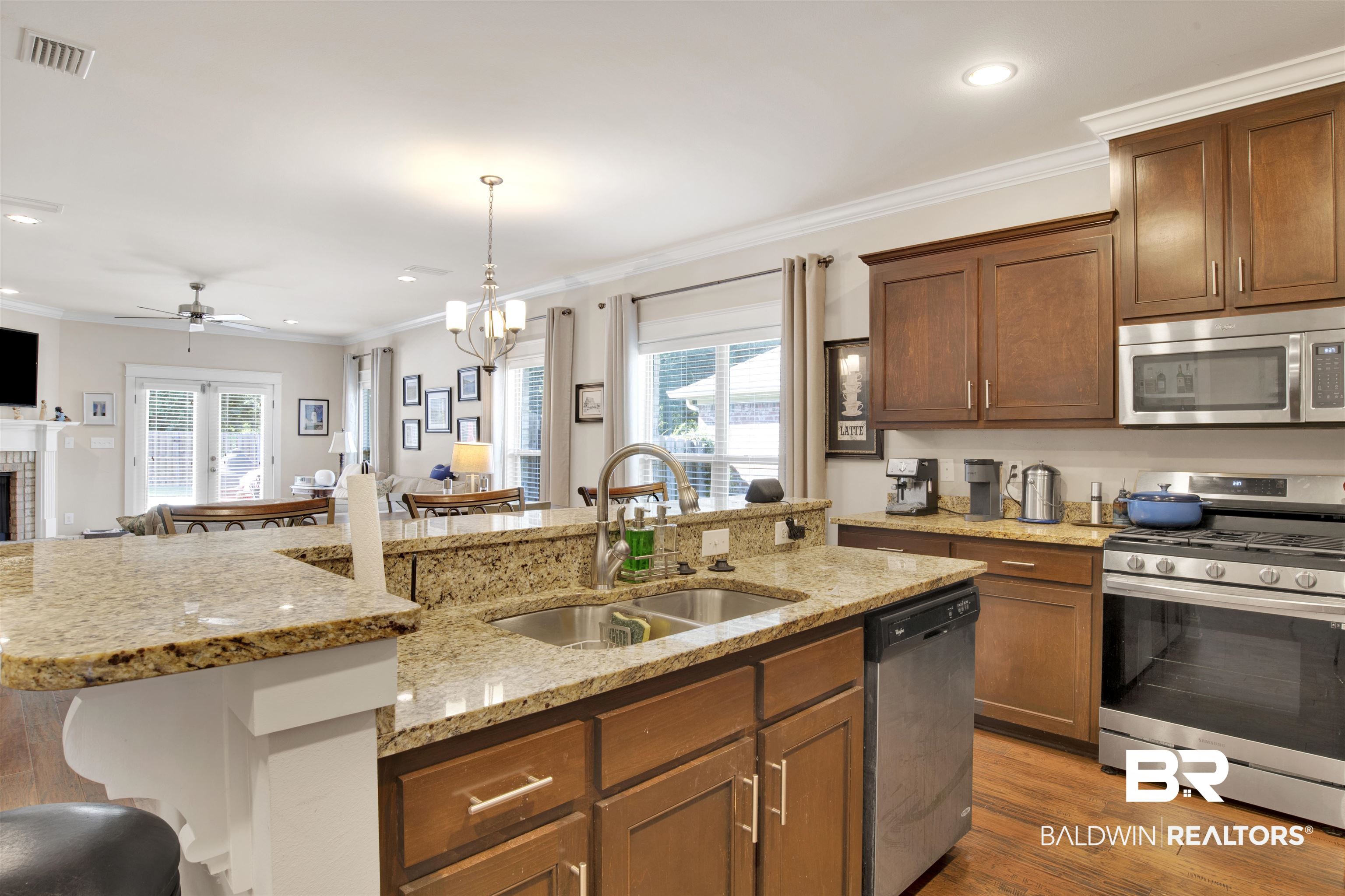 360 Scarlett Avenue Fairhope, AL 36532 - Photo 11 of 34 Kitchen featuring appliances with stainless steel finishes, dark wood-type flooring, a brick fireplace, ornamental molding, and sink