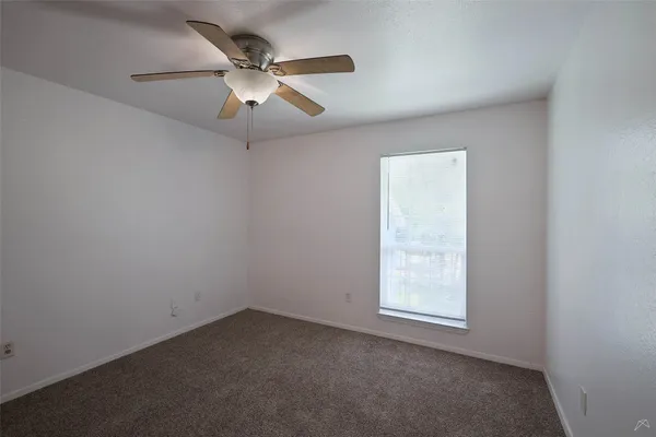 an empty room with a fan & a ceiling fan