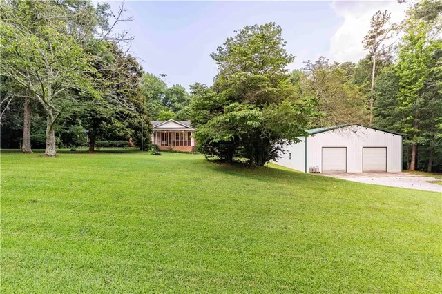 a white house with a big yard and large trees